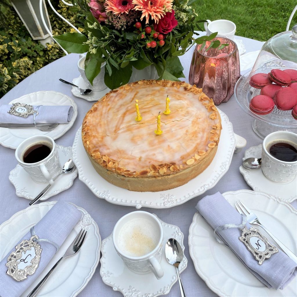 Französisches Ambiente auf der festlichen Kaffeetafel Leinenservietten mit Serviettenring als Medaillon von Lobreon und Tischdecke hellgrau TorteMacarons und Blumen 